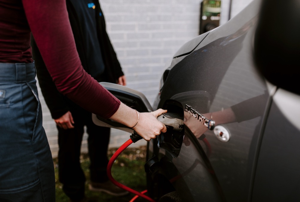 Someone plugging in a charger to an electric vehicle.jpg